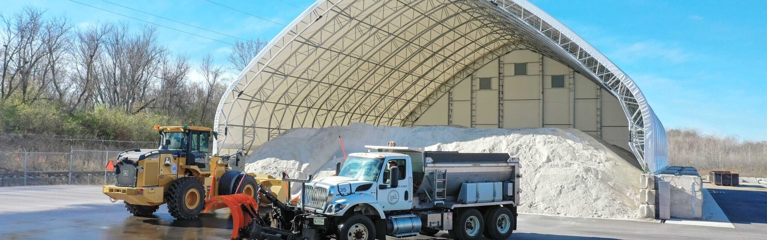 vehicles in front of a fabric sand and salt building