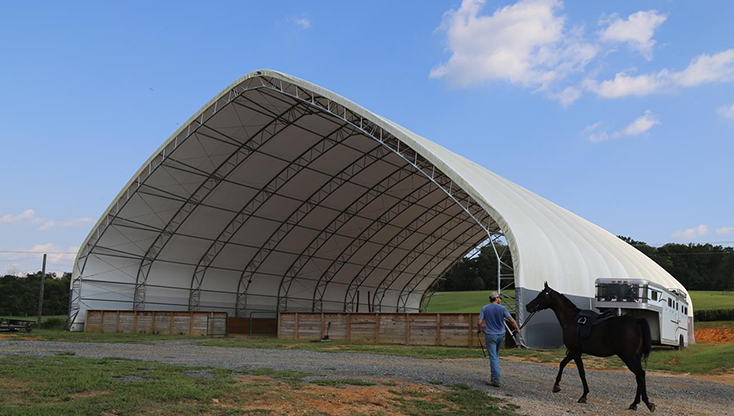 Walking his horse to fabric horse riding arena