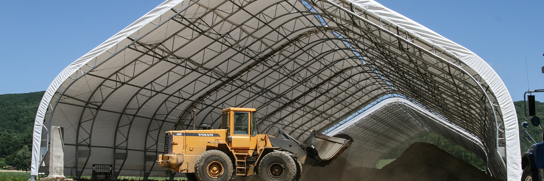 Yellow Dozer moving material under a fabric building