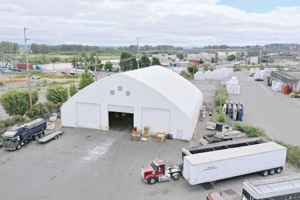 gable fabric building surrounded by trucks and materials