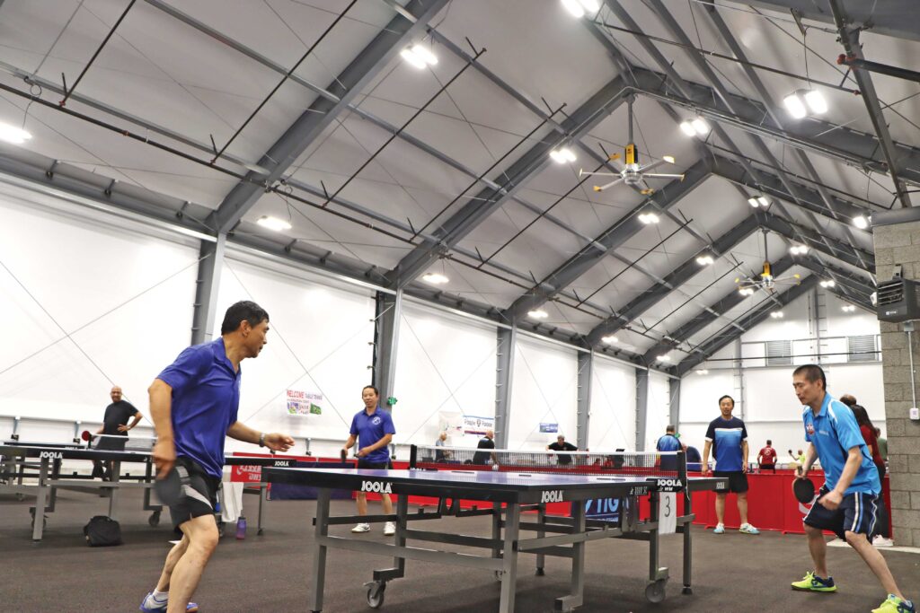 people playing table tennis inside fabric beam building