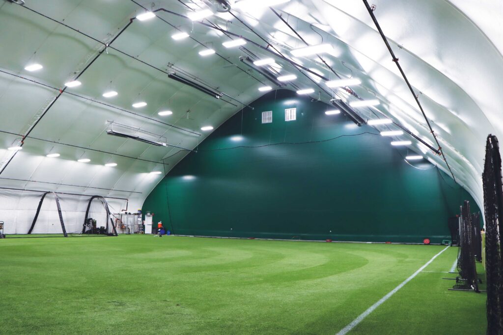 indoor practice facility with grass field and light fixtures