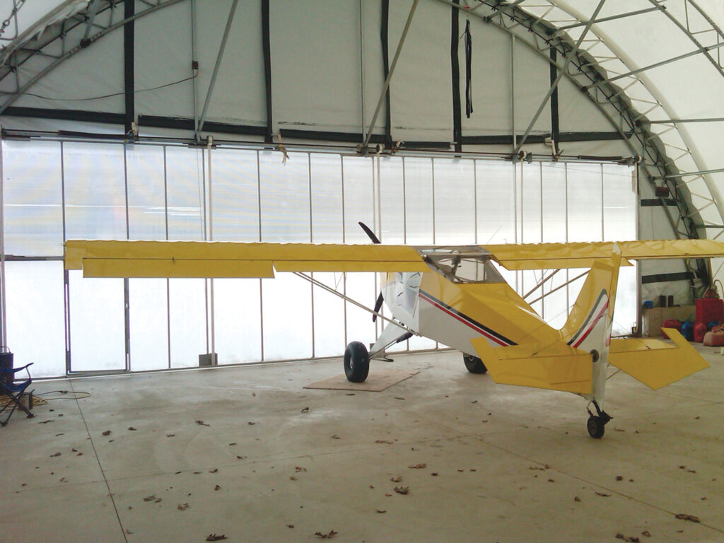 small personal plane inside fabric hangar