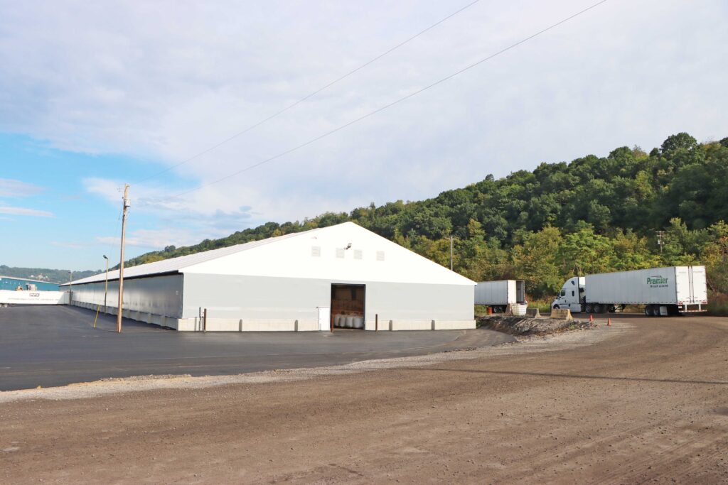 fabric beam building with water and trees in background