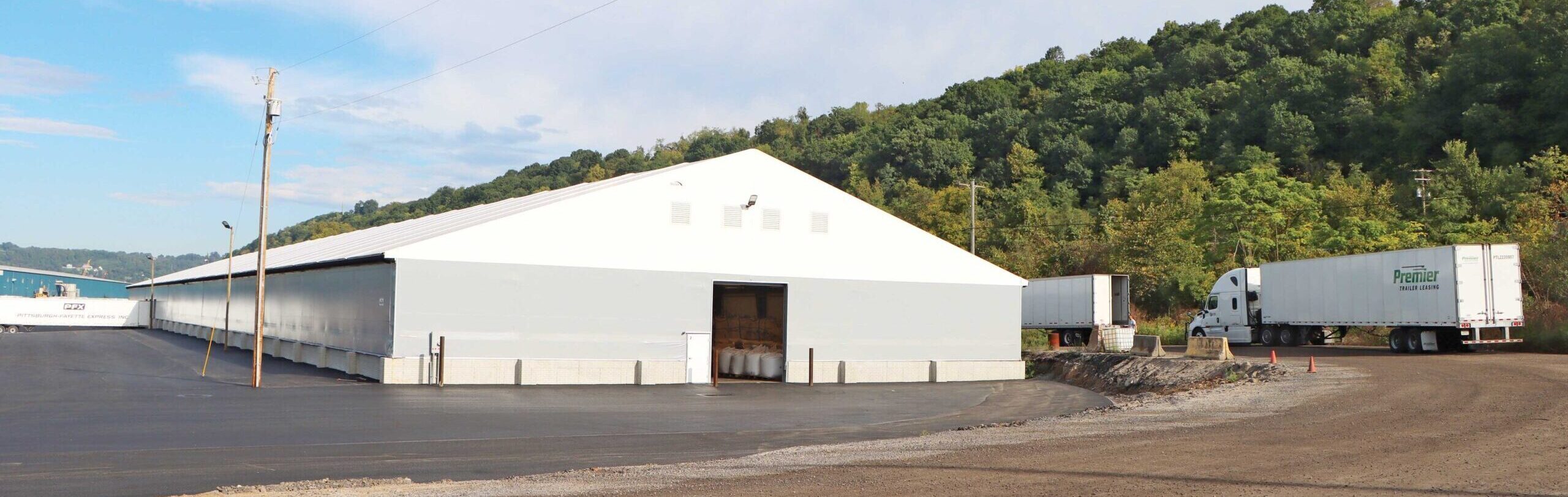 fabric beam building with water and trees in background