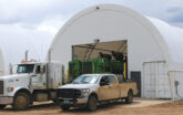 Trucks parked outside two ClearSpan truss arch buildings