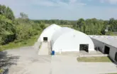 two white fabric warehouse buildings with trees and landscaping in the background