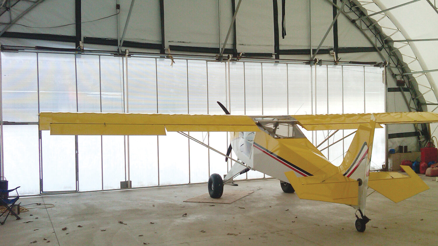 small personal plane inside fabric hangar