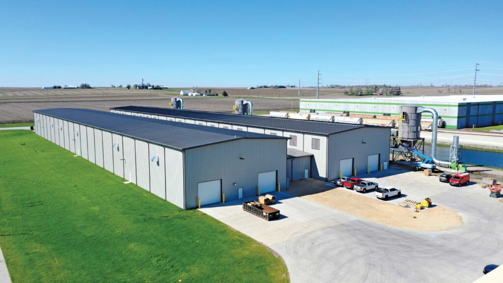 Two Metal Buildings side by side with bay doors and vehicles parked in front