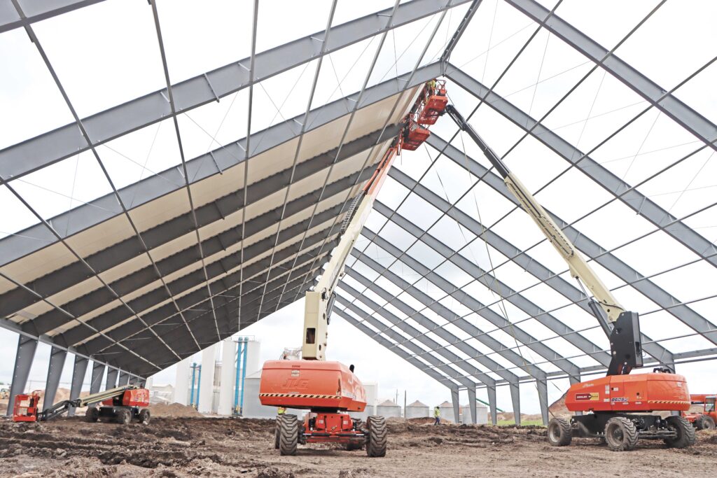A fabric cover being installed on a ClearSpan HD Beam Building; interior view